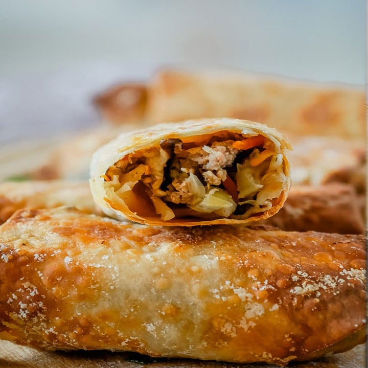 A photo of the interior of a crispy egg roll filled with meat and cabbage.